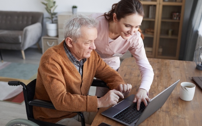 nurse helping an older adult to use a computer