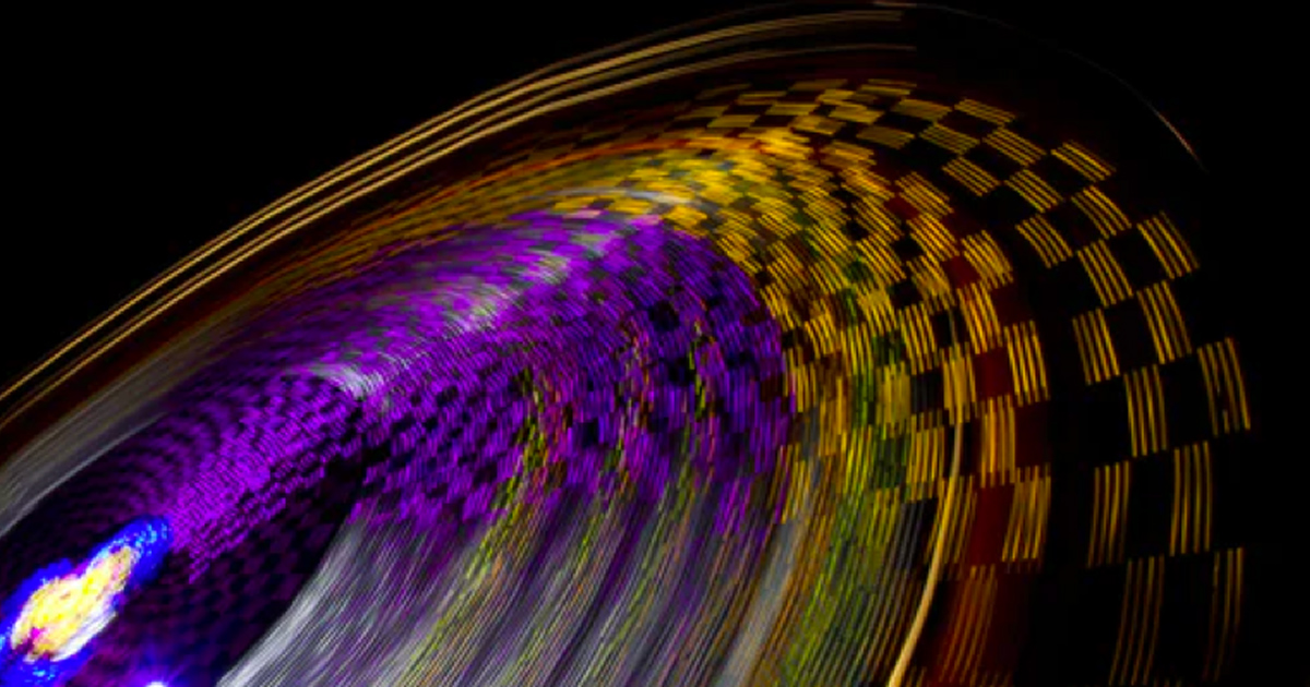 Colorful carnival ride light trails spinning in the dark.