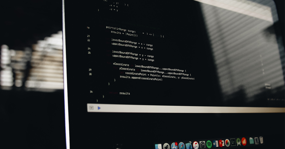 Laptop screen showing code in a dark room.