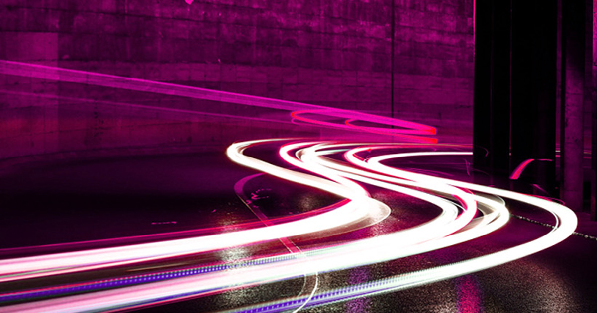 Pink and white light trails curving through the dark.