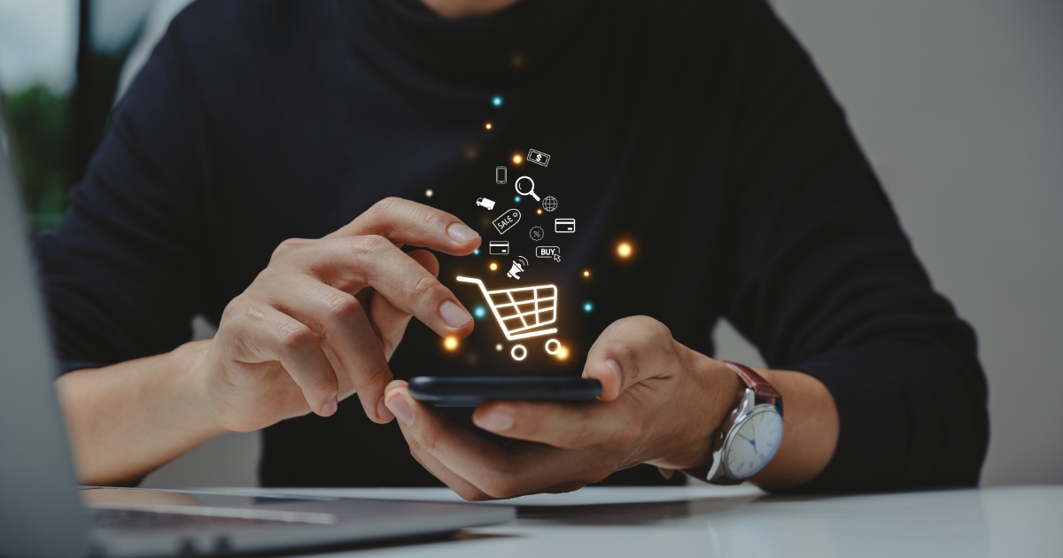 Person using a phone with shopping icons floating above the screen.