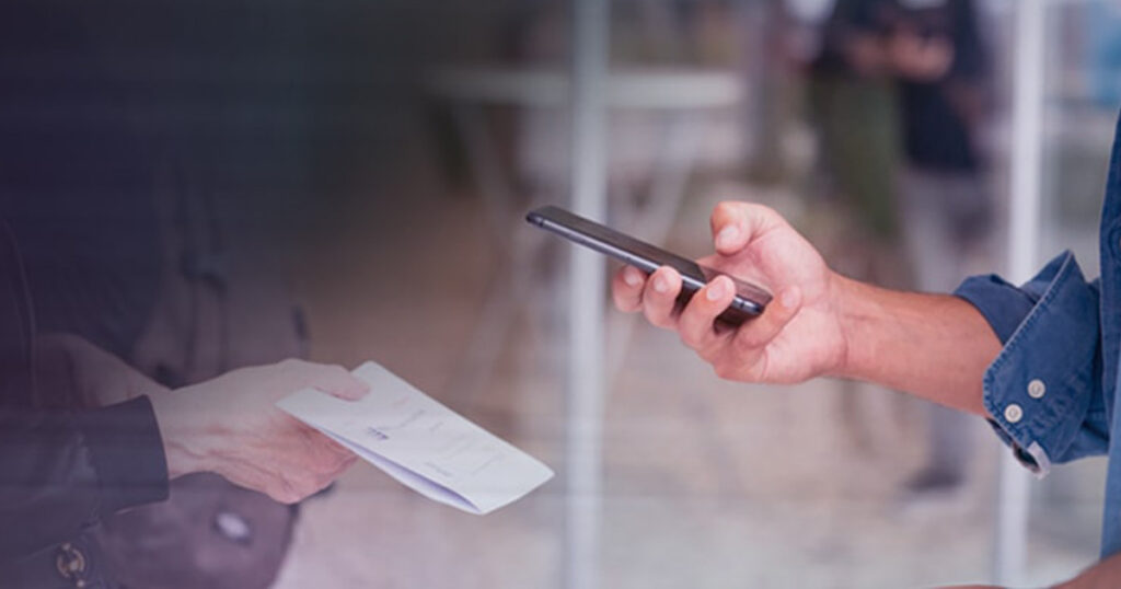 Hand holding a phone scanning a QR code from a paper document.