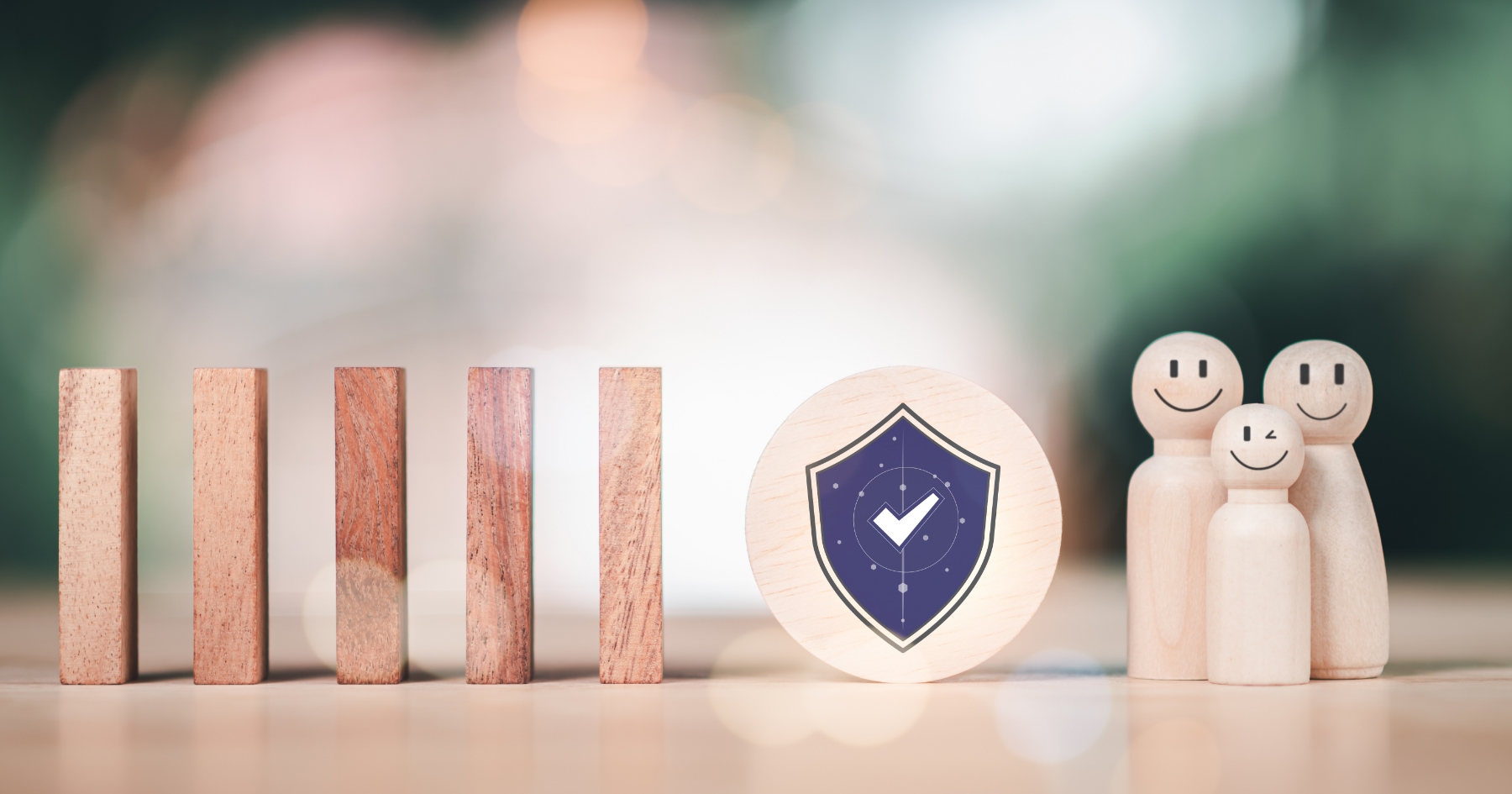 Wooden blocks lined up beside miniature smiling figures with a shield-and-checkmark badge between them, representing insurance management protection.
