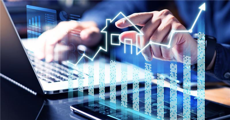 Hands typing on a laptop with a glowing overlay of rising financial charts and a house icon, representing AI agents at work in banking.