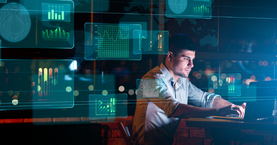 Analyst working at a desk surrounded by translucent floating dashboards and charts, representing milestones toward faster enterprise decisions.