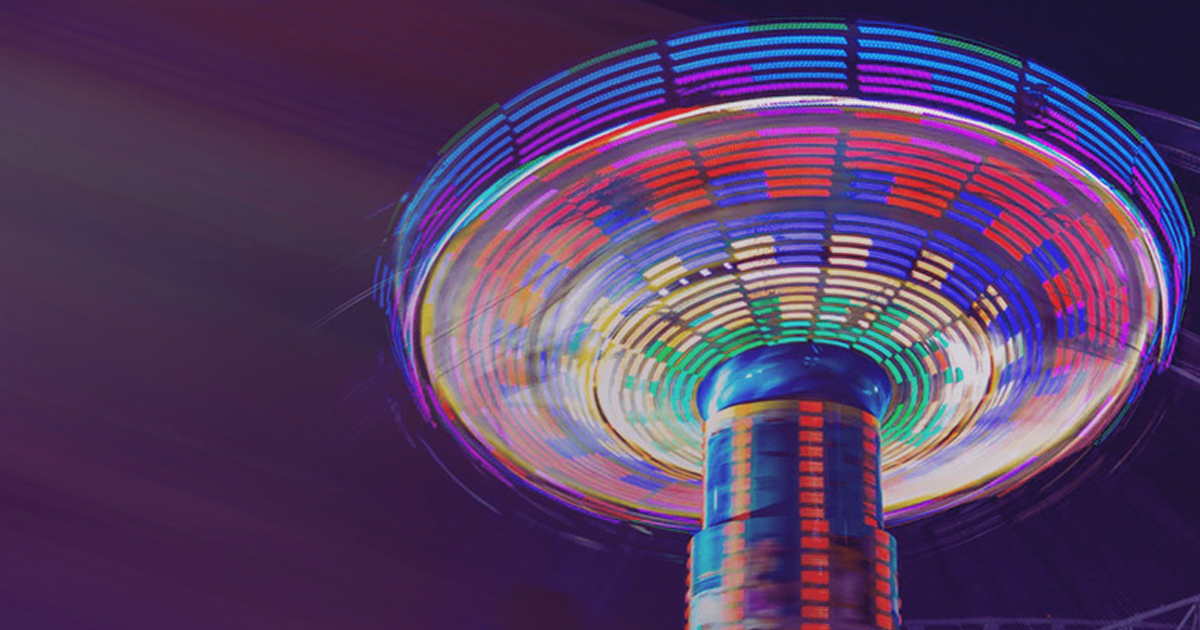 Colorful carnival swing ride spinning in long-exposure motion blur, representing controlled experimentation in an innovation lab.