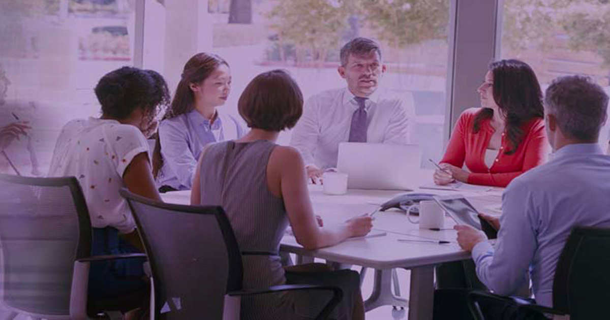 Colleagues collaborating around a table in a bright meeting room.