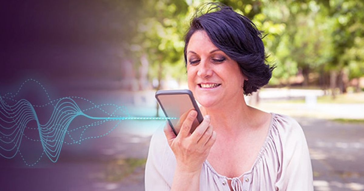 Smiling woman speaking to a voice assistant on her phone outdoors with a sound wave graphic, representing conversational insurance chatbots.