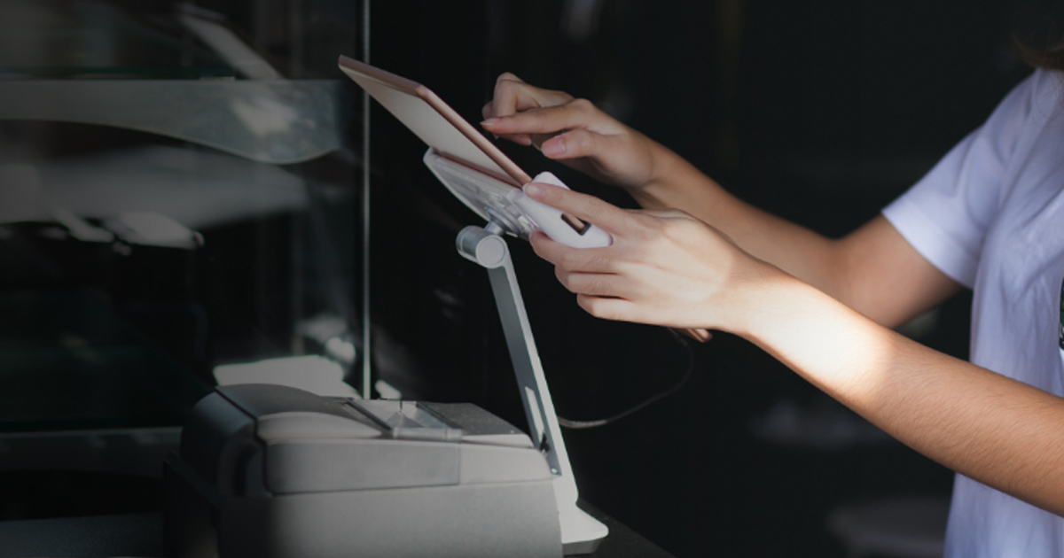 Hands exchanging a takeout order at a restaurant counter kiosk, representing competition with ghost kitchens for online orders.