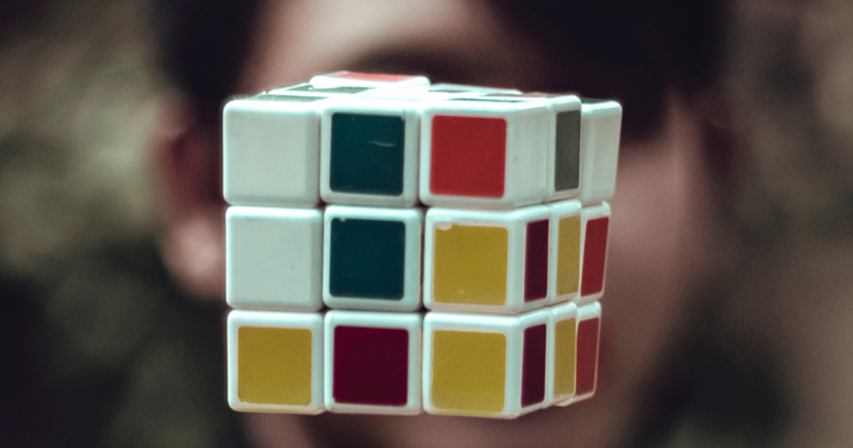 Rubik's cube with muted color squares held in focus, representing architecture fitting business strategy together.