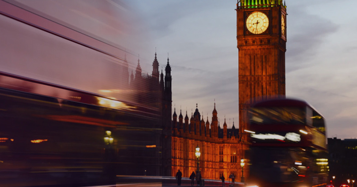 Big Ben and a blurred red double-decker bus at dusk, representing digital transformation in UK higher education.