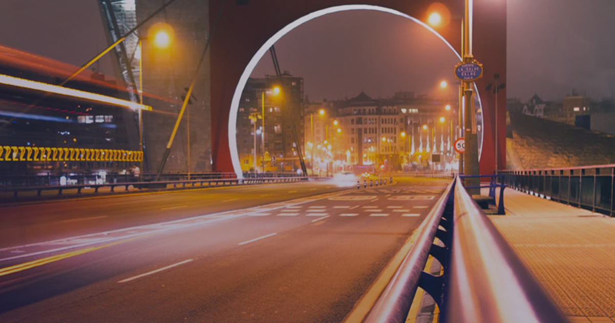 Night highway with light trails passing under a glowing arch bridge, representing sprint speed and flow explained with Little's Law.