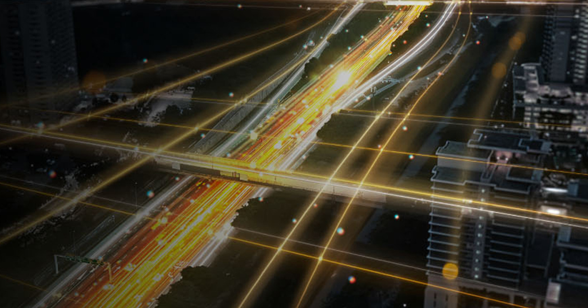 Aerial night view of a highway junction with glowing traffic trails.