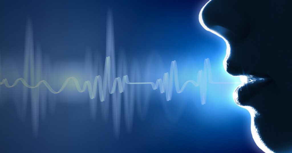 Profile of a face with a glowing voice waveform, representing speech technology.