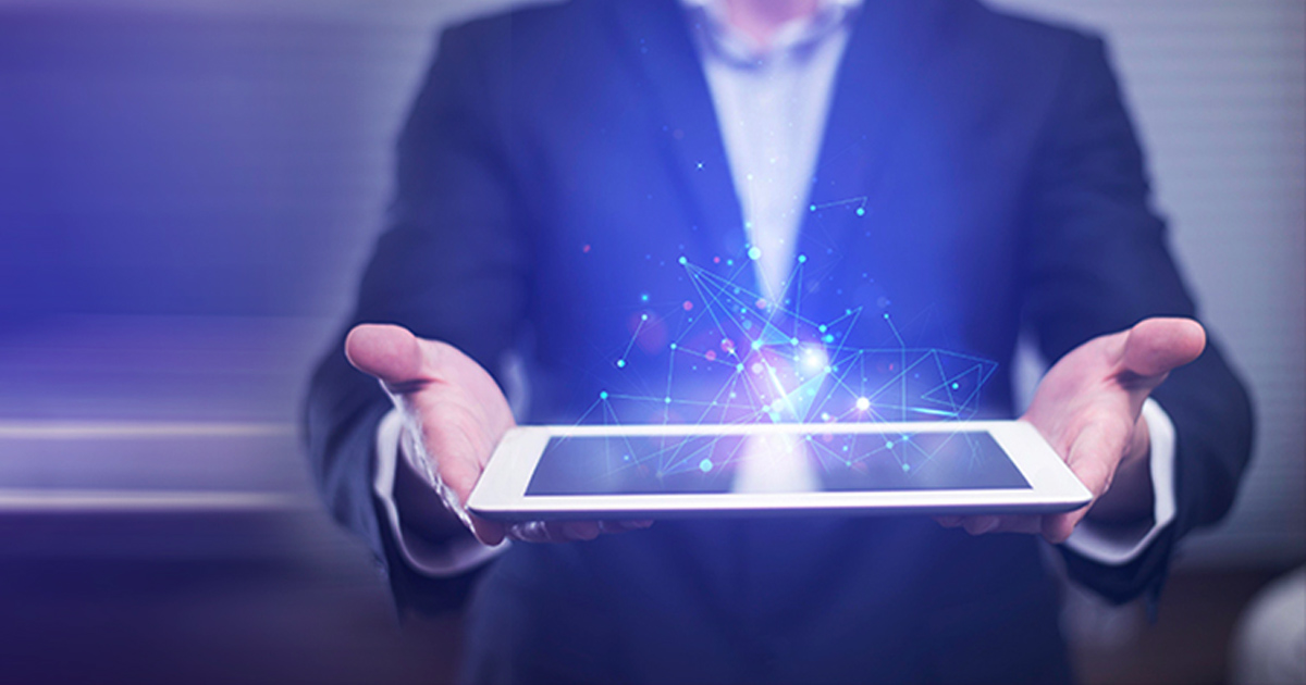 Businessman holding a tablet with sparkling light rising from the screen.