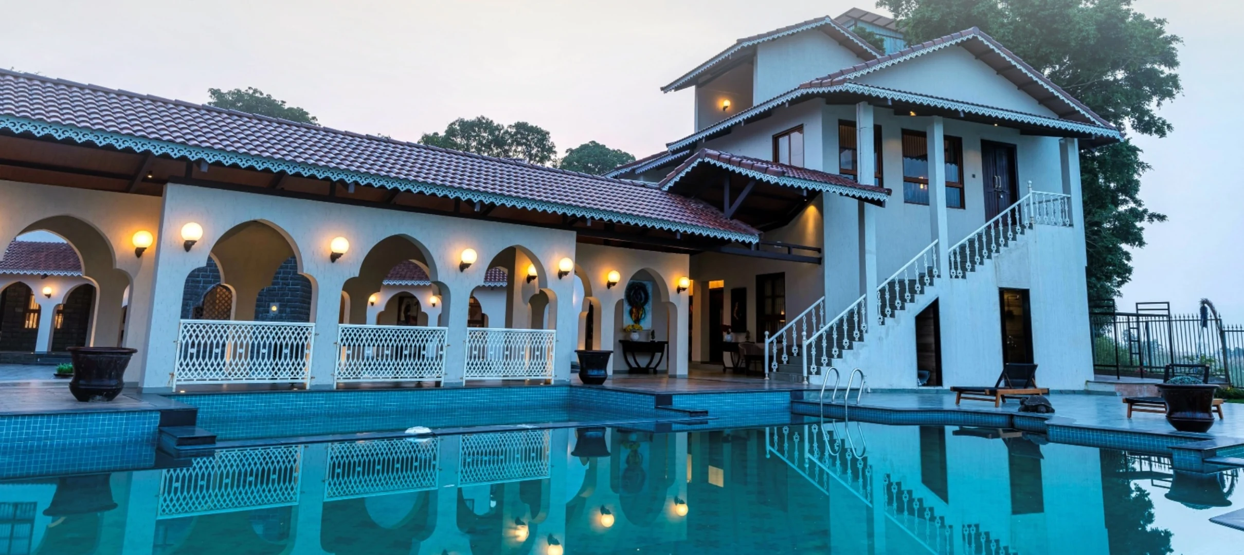 Luxury villa with arched veranda and swimming pool at dusk